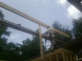 Carpenter setting a ridge beam over a new addition frame — Ice Dam Removal by Roofing Brothers in Hilham