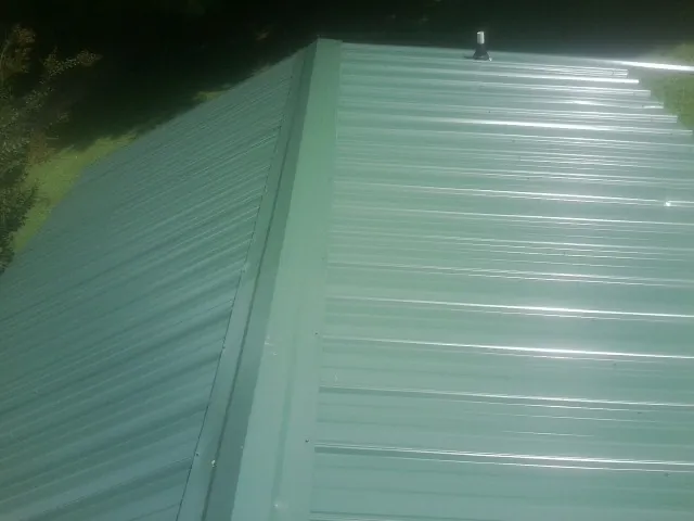 New green metal panels meeting at the ridge of a roof — Flat Roof Repair work by our crew in Hilham