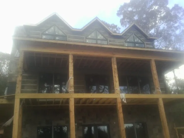 Dormers and porch framing on a large log home under construction — Roof Coating work by our crew in Hilham