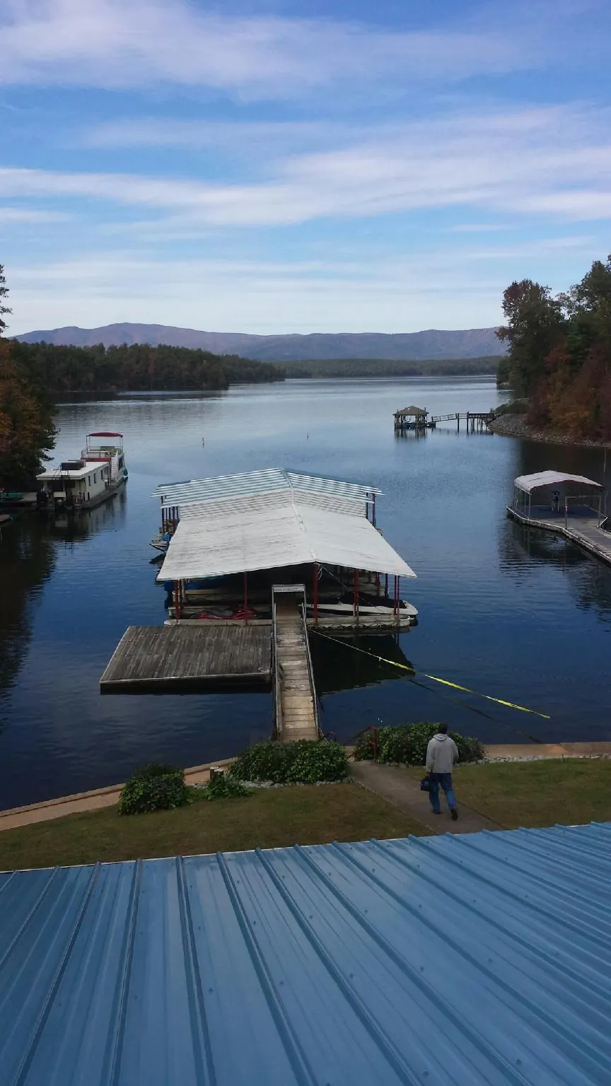 View across a lake from a newly installed blue metal roof in Hilham