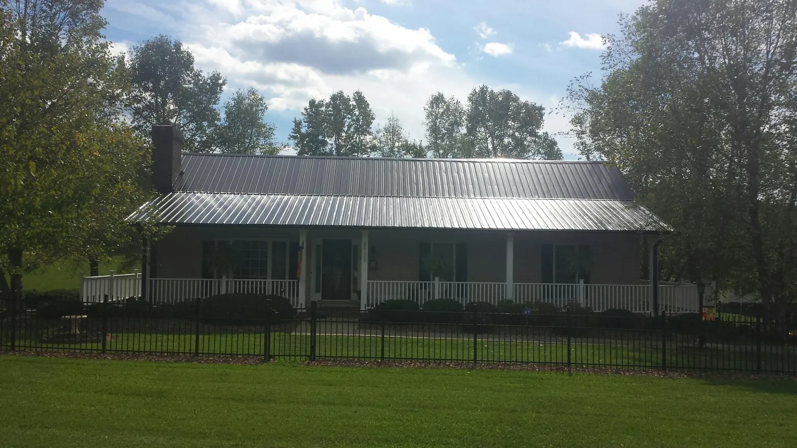 Gray metal roof on a brick ranch with a full width front porch — Gutter Guard Installation work by our crew in Hilham