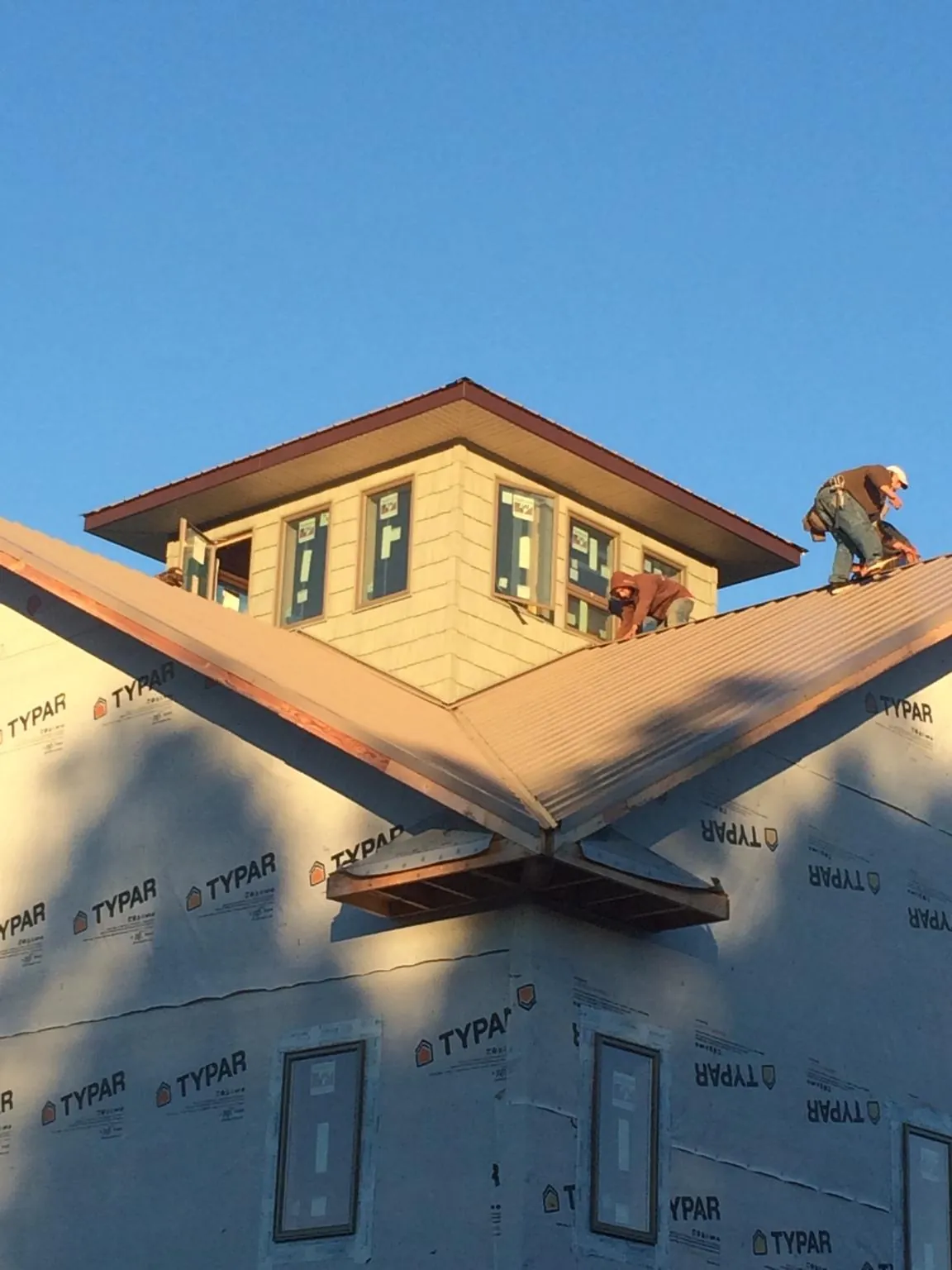 Roofers working around a rooftop cupola on a new metal roof at sunset — Roof Waterproofing in Hilham by Roofing Brothers